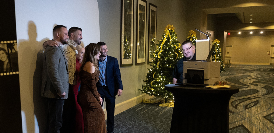A small group of event attendees pose for a photo in front of a green screen