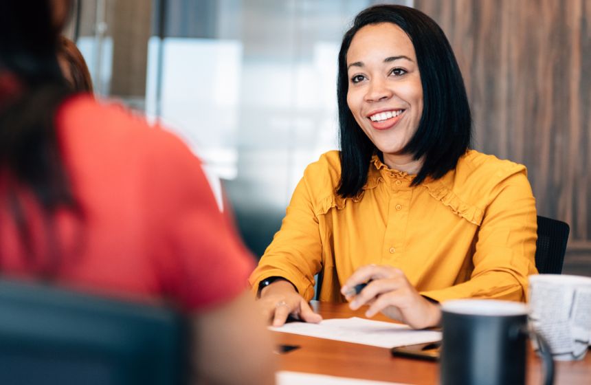 Two women talking and writing down notes.