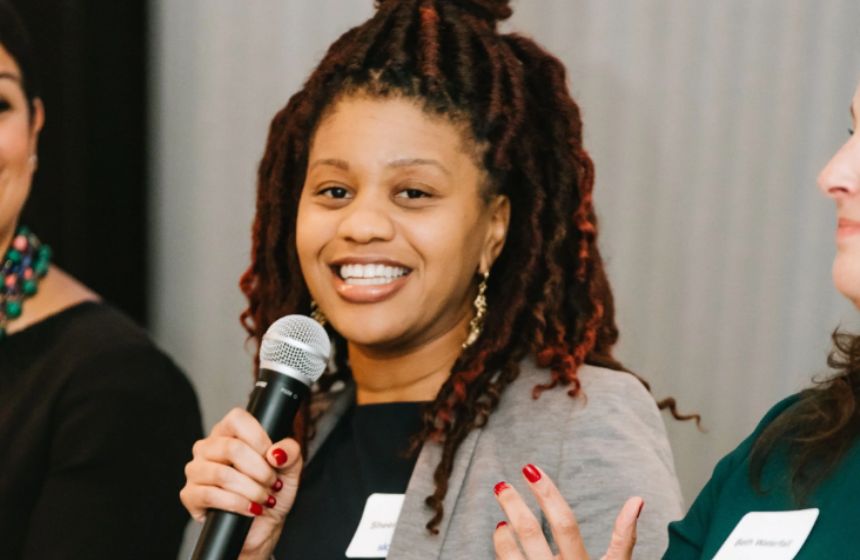 A woman smiling holding a microphone.
